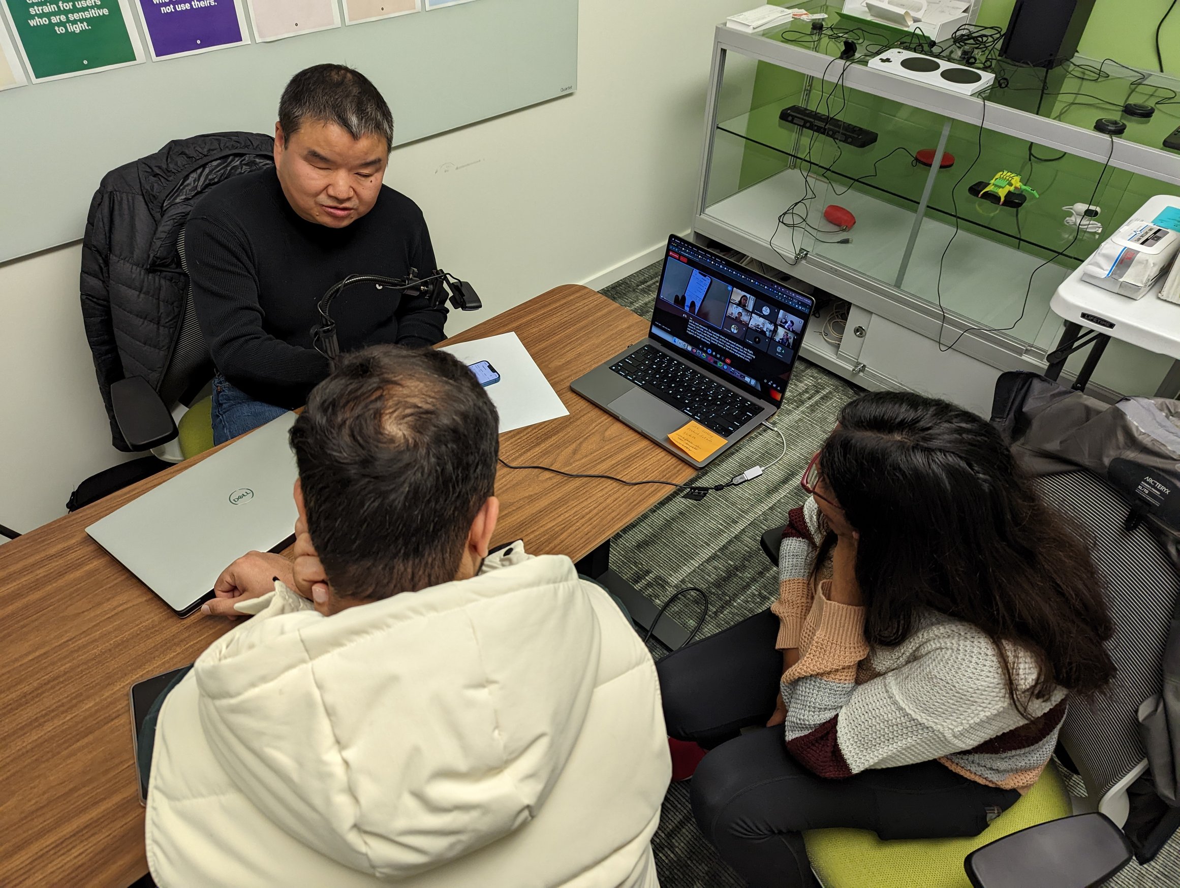 Young Choi using a screen reader to navigate a website while two Googlers watch the demo in an accessibility lab